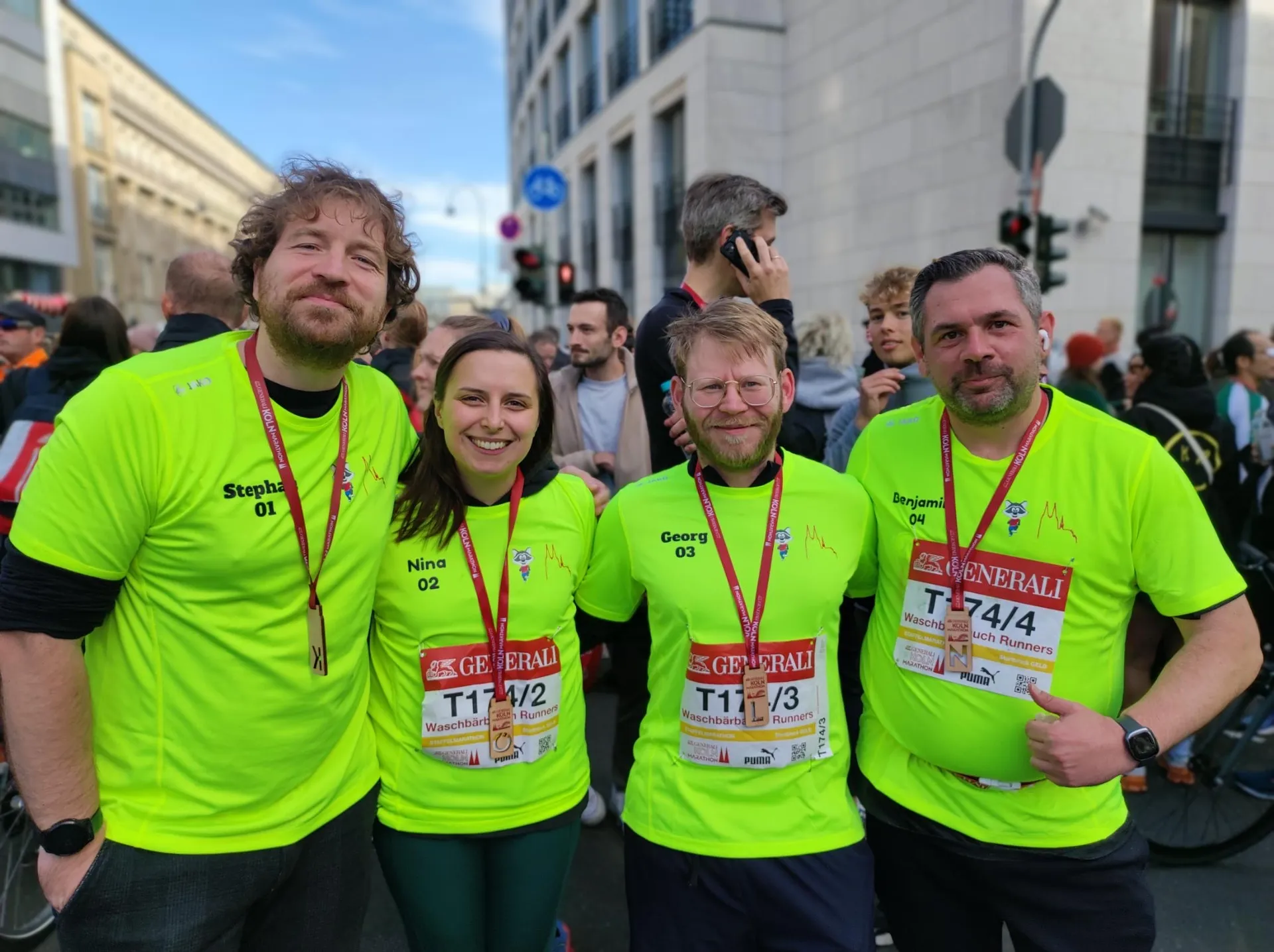 Gruppenphoto meines Staffelmarathon-Teams „Waschbärbauch Runners“ in unserem neongelben Team-Trikot und mit Medaille hinter dem Zielbereich.