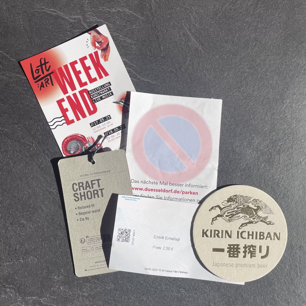 Die Zettelwirtschaft nach einem Tag in Düsseldorf: Flyer für einen Kunstmarkt, Hosen-Label vom Shoppen, Eintrittskarte vom Filmmuseum, japanischer Bierdeckel und ein Knöllchen.